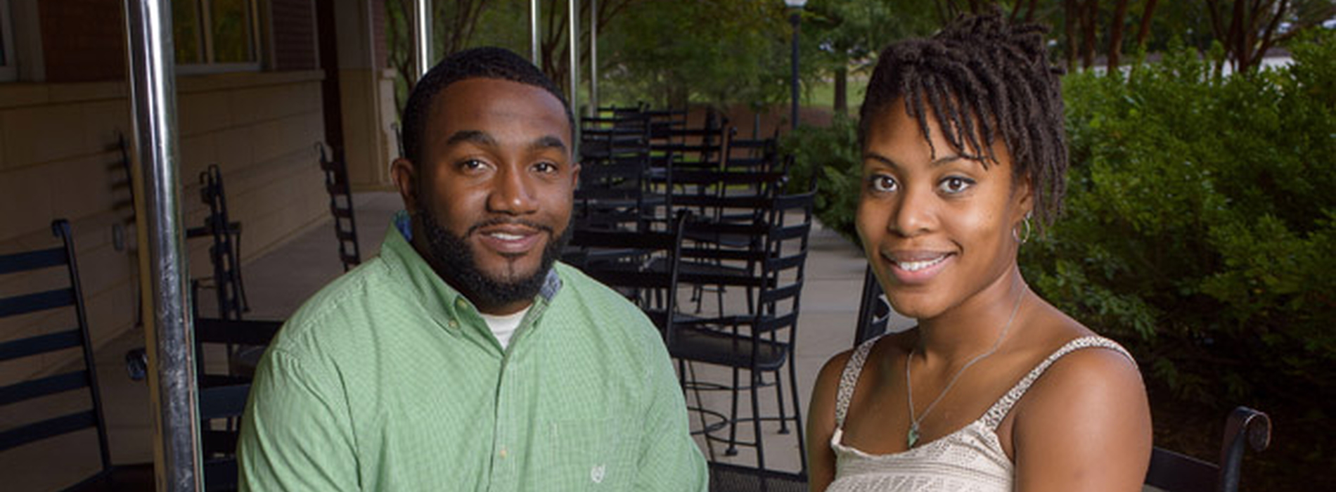 Man in green dress shirt sits at a table with a woman in a white dress