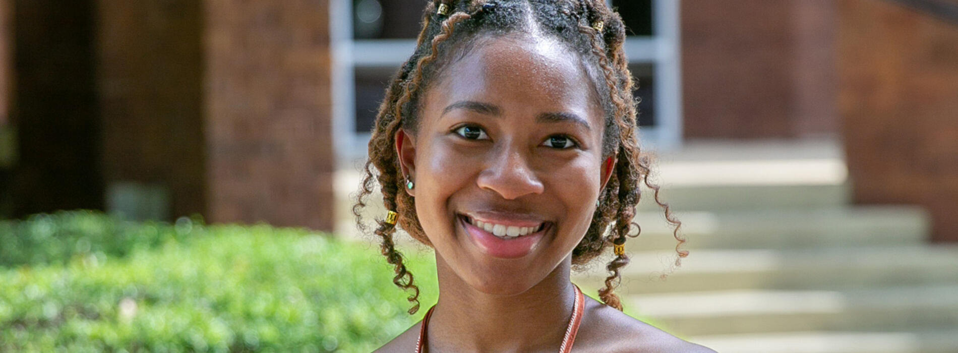 A young woman wearing a burnt orange and white striped shirt and smiling.
