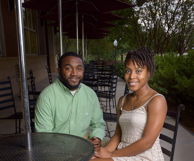 Man in green dress shirt sits at a table with a woman in a white dress