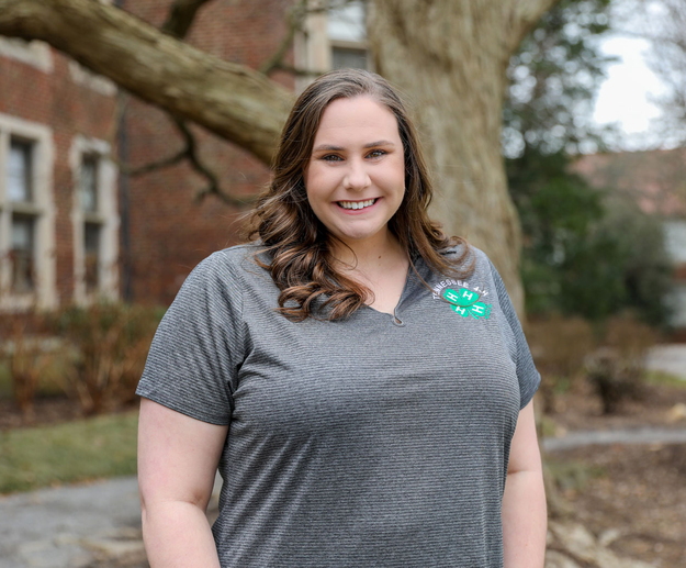 A standing woman smiling and wearing a Tennessee 4-H polo.